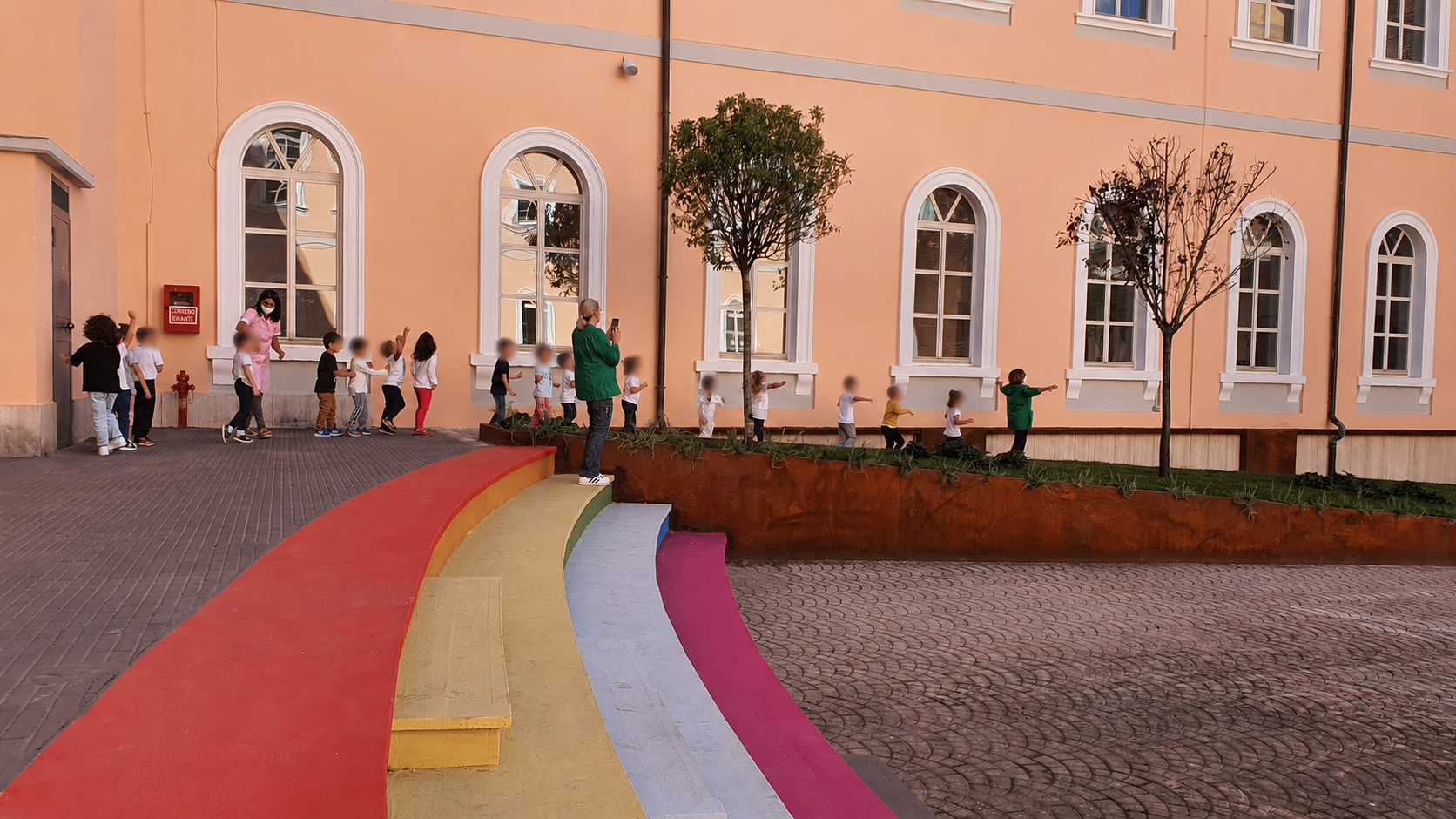 Bambini nella corte del Palazzotto con i volti rivolti alla camera resi non riconoscibili